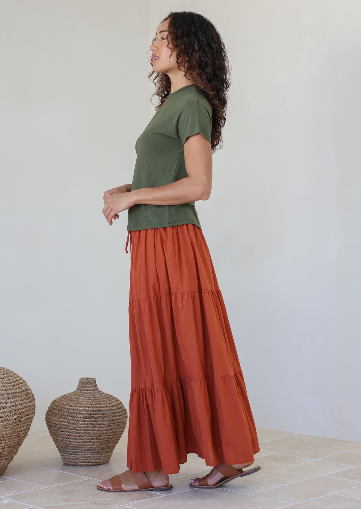 Model wearing a plain rust shade skirt with elasticated and drawstring waistband.