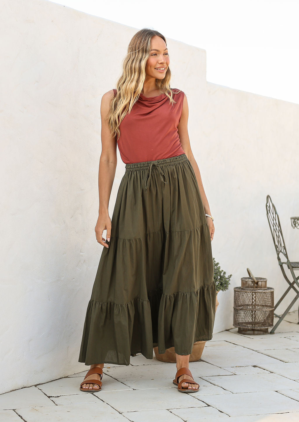 women wearing a 100% cotton olive green skirt with a pink plain top standing against a white background.
