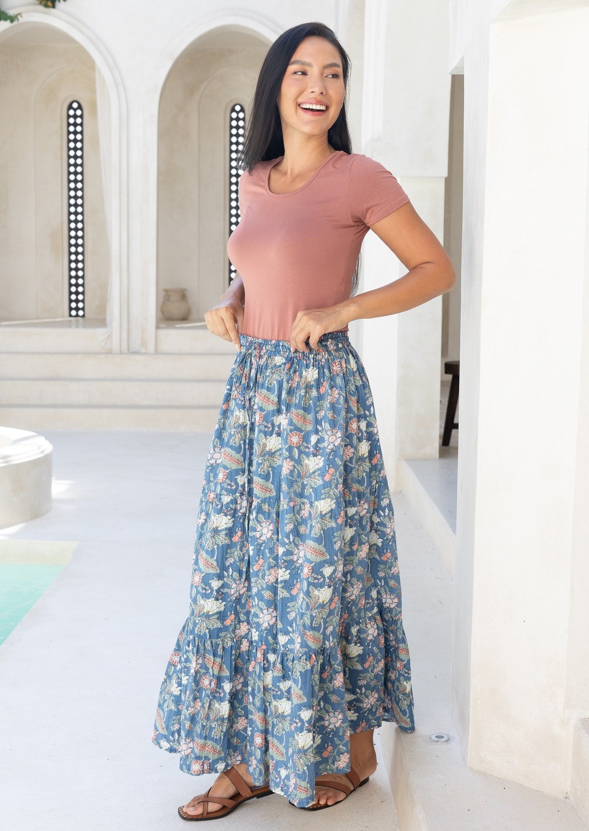 Woman wearing a pink top and blue cotton floral maxi skirt with an elastic waitband and a drawstring