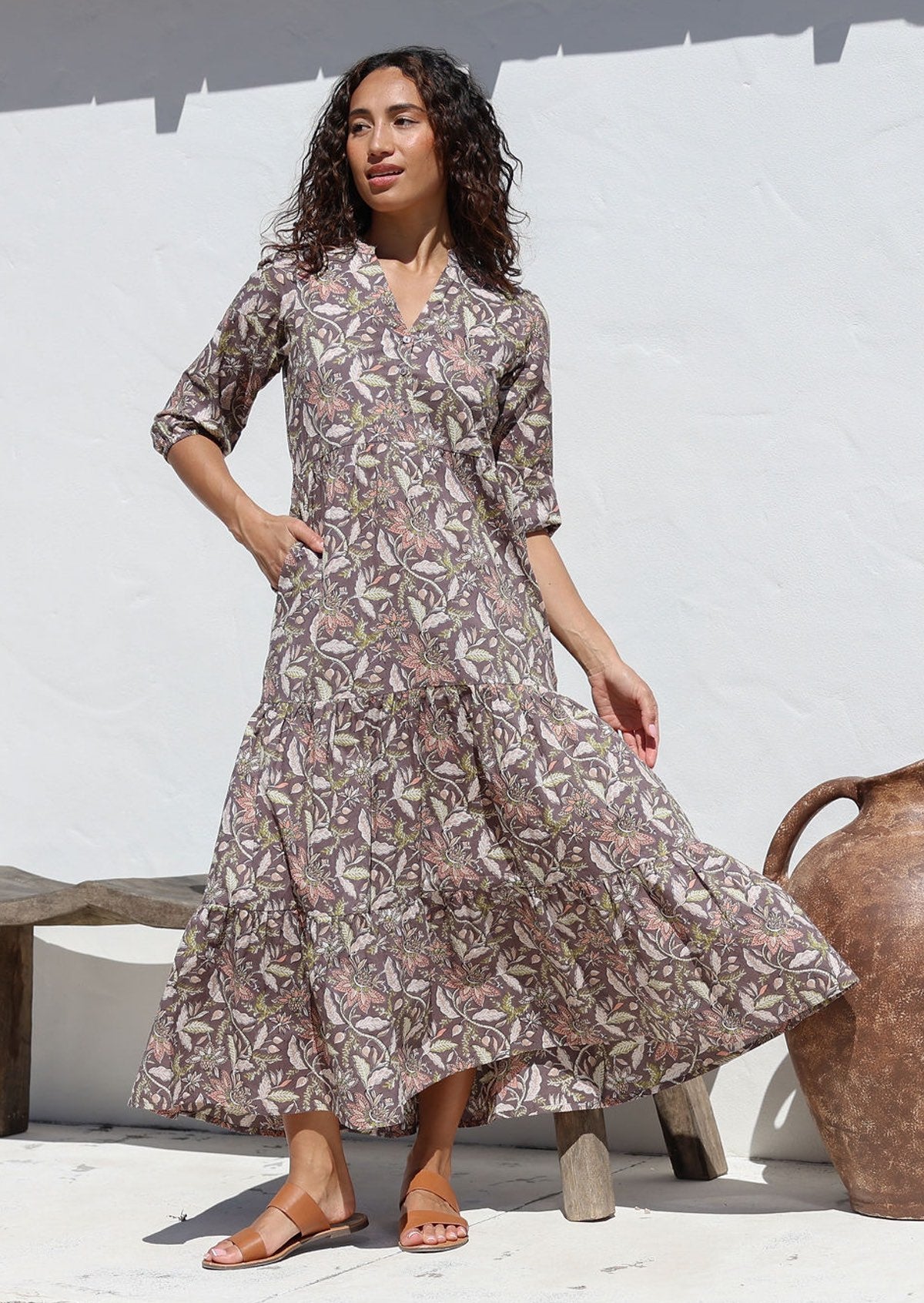 Model wears taupe based floral maxi dress with buttoned bodice, mandarin collar, 3/4 sleeves and pockets