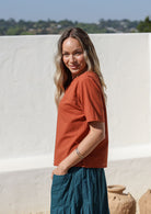 women wearing a 100% cotton rust shade top with a blue pants standing against a white background.