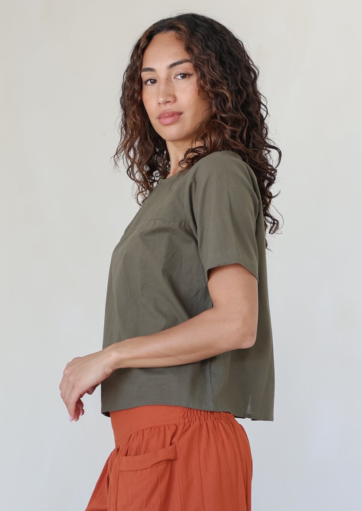 women wearing a 100% cotton olive green shade top with a rust pants standing against a white background.