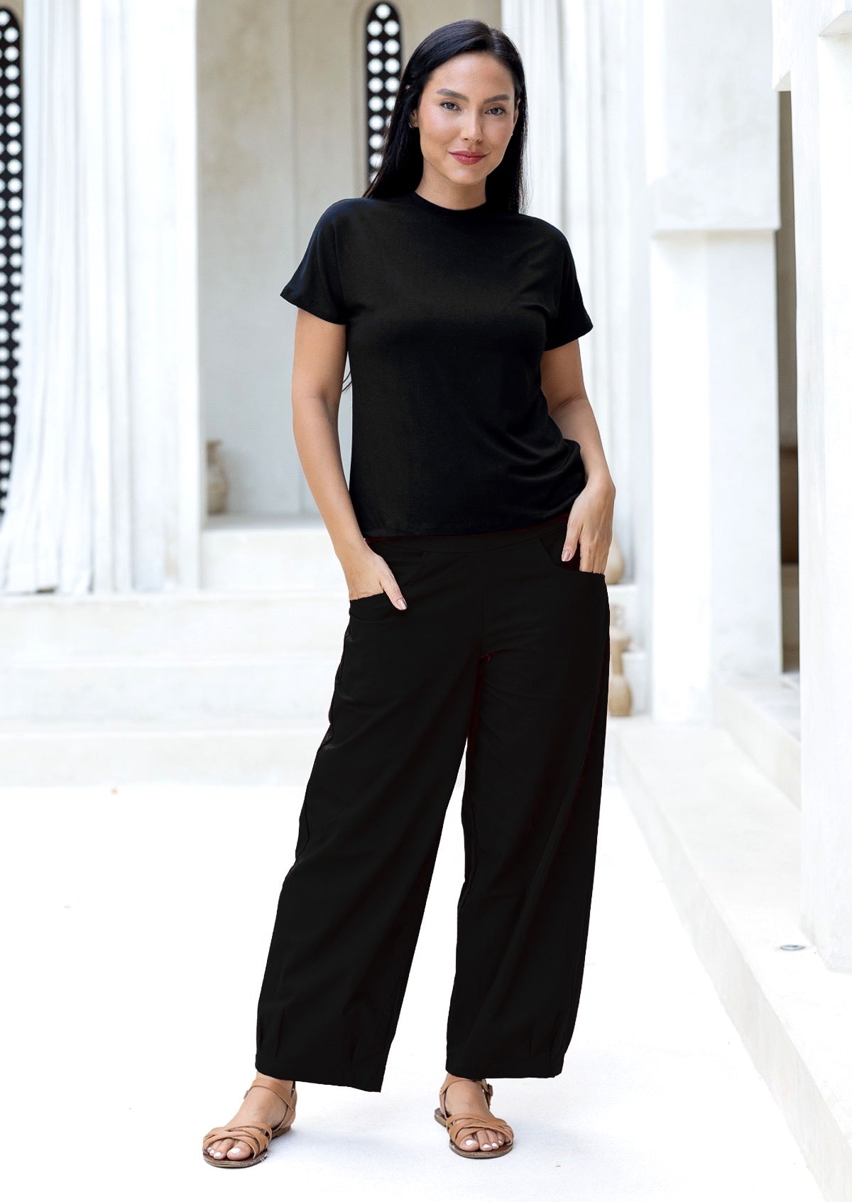 Woman wearing a black t-shirt and black cotton pants in a white villa

