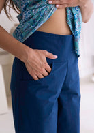 Model with hand in pocket wearing a 100 percent cotton deep sea blue pants with side zipper and wide leg fit