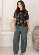 Woman wearing jungle green wide leg cotton pants with black floral top.