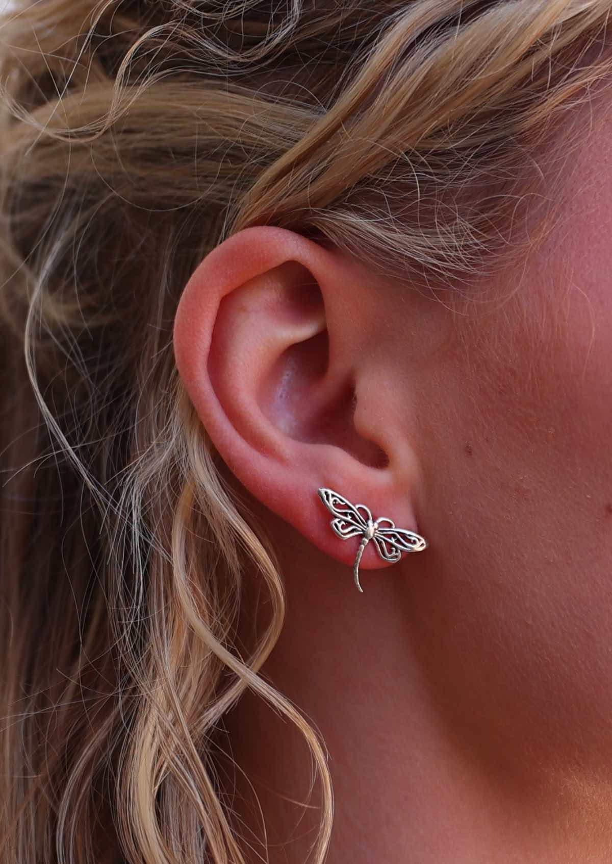 Close up of large sterling silver dragonfly stud earrings in model's ear
