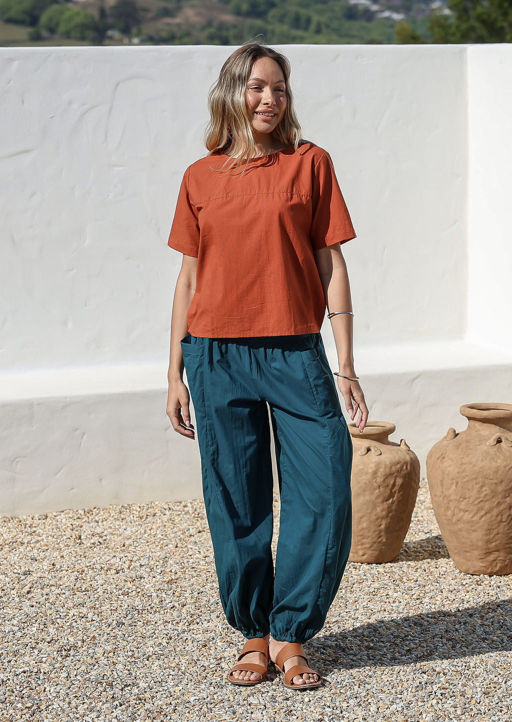 Models poses in deep teal cotton wide leg pants with elasticated ankle