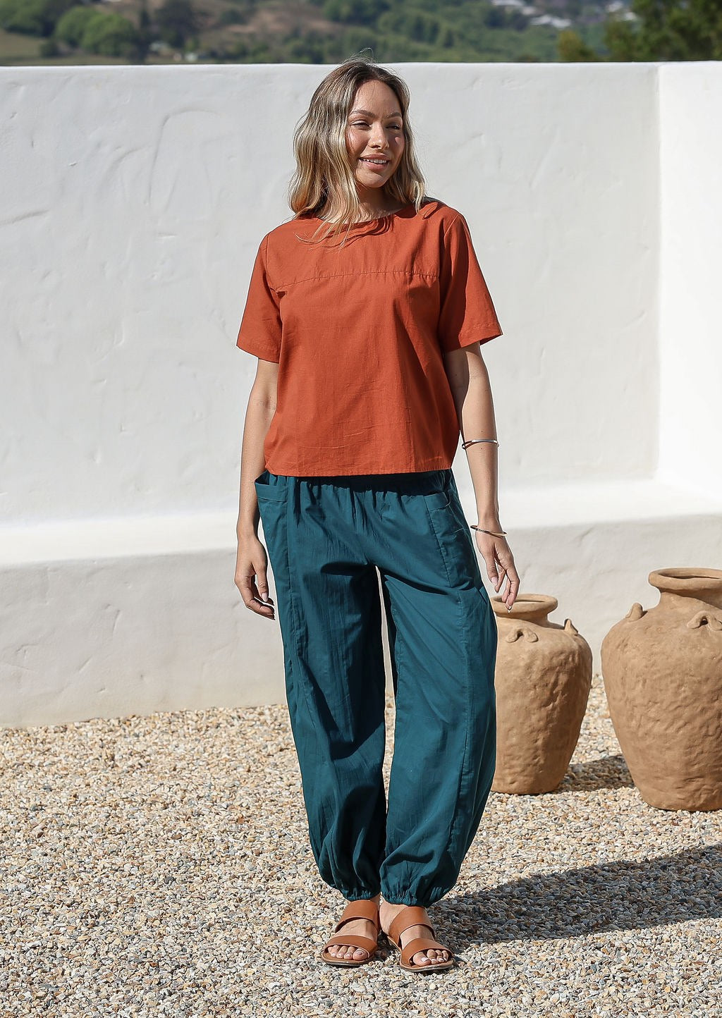 Models poses in deep teal cotton wide leg pants with elasticated ankle