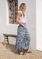 Side pose of model wearing a floral cotton pants with elastic ankles and waist.