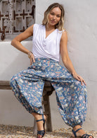 Woman sitting on a wooden bench in 100% cotton harem pants with elasticated ankles and deep pockets.