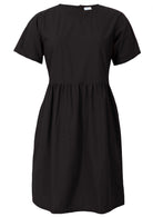 Loose fitting above knee length plain black cotton dress with short sleeves, high round neckline and pockets