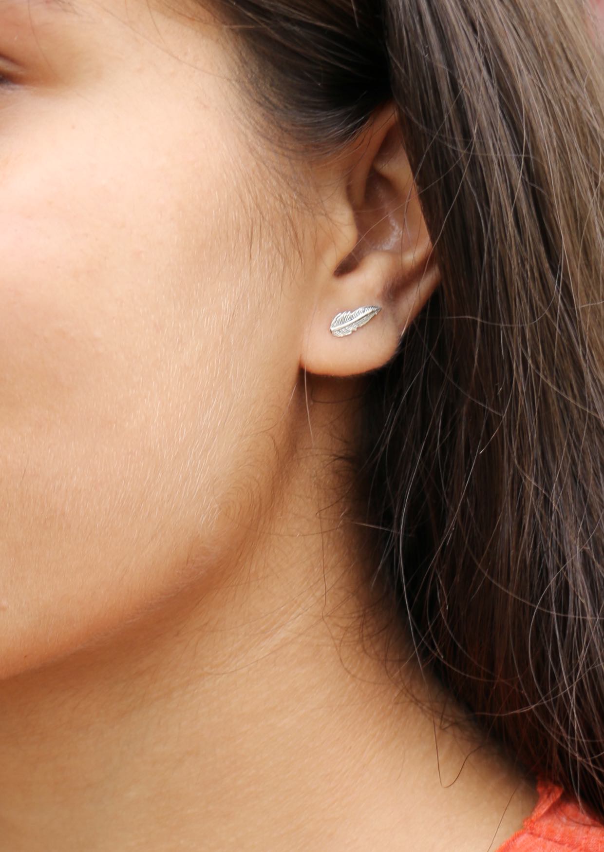 Close-up of a person wearing a plumage silver studs with delicate feather design