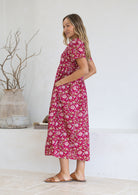 Woman wearing a pink floral dress with her hand in the pocket 