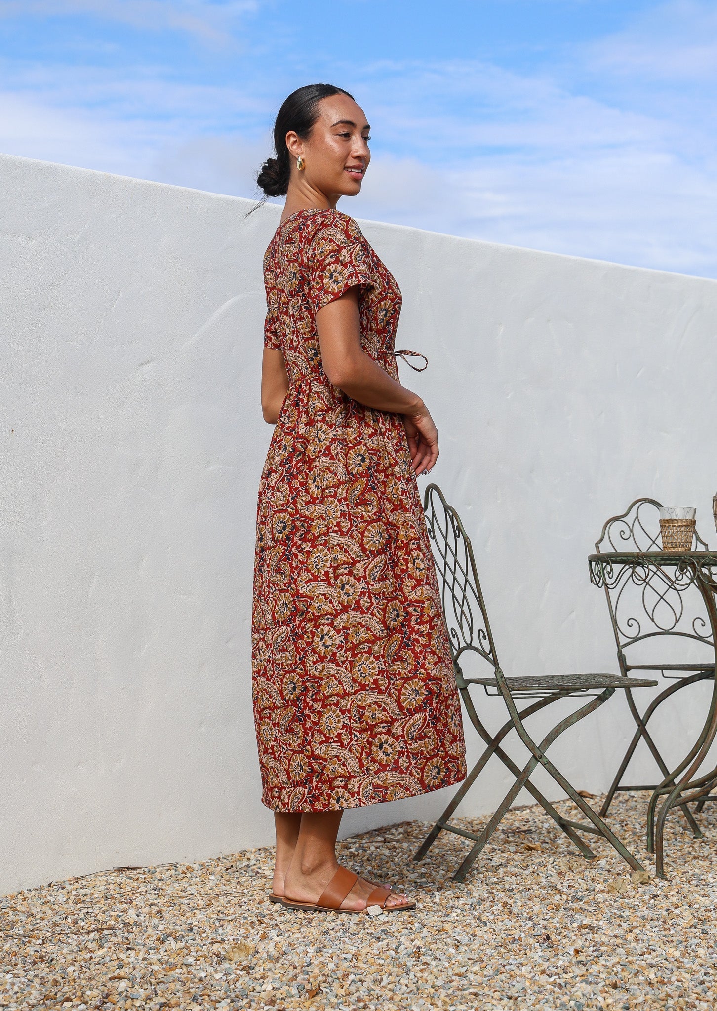 Model posing sideways in a cotton button through relaxed fit shin length dress with V-neckline and T shirt sleeves.