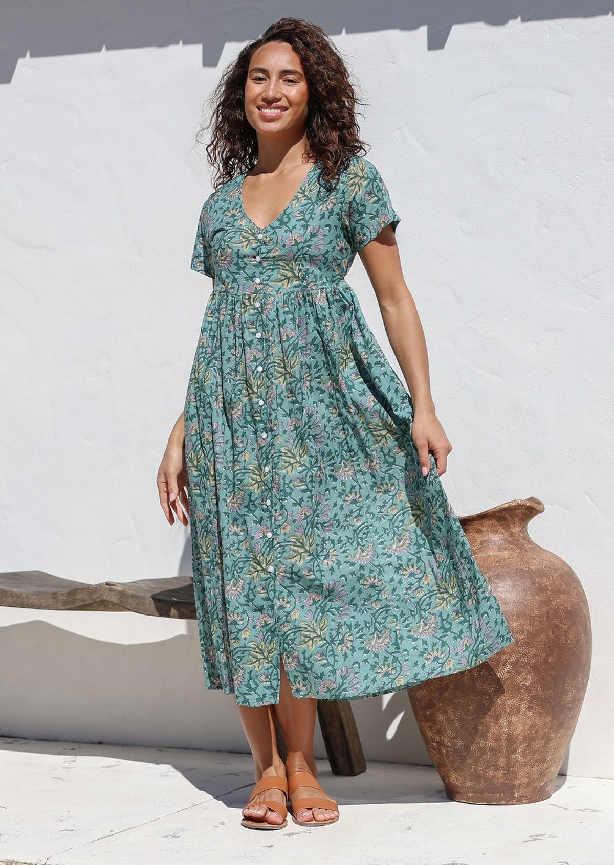 Model wears sage green floral print  midlength cotton dress with V neckline, button front, shoestring tie at empire waist and pockets