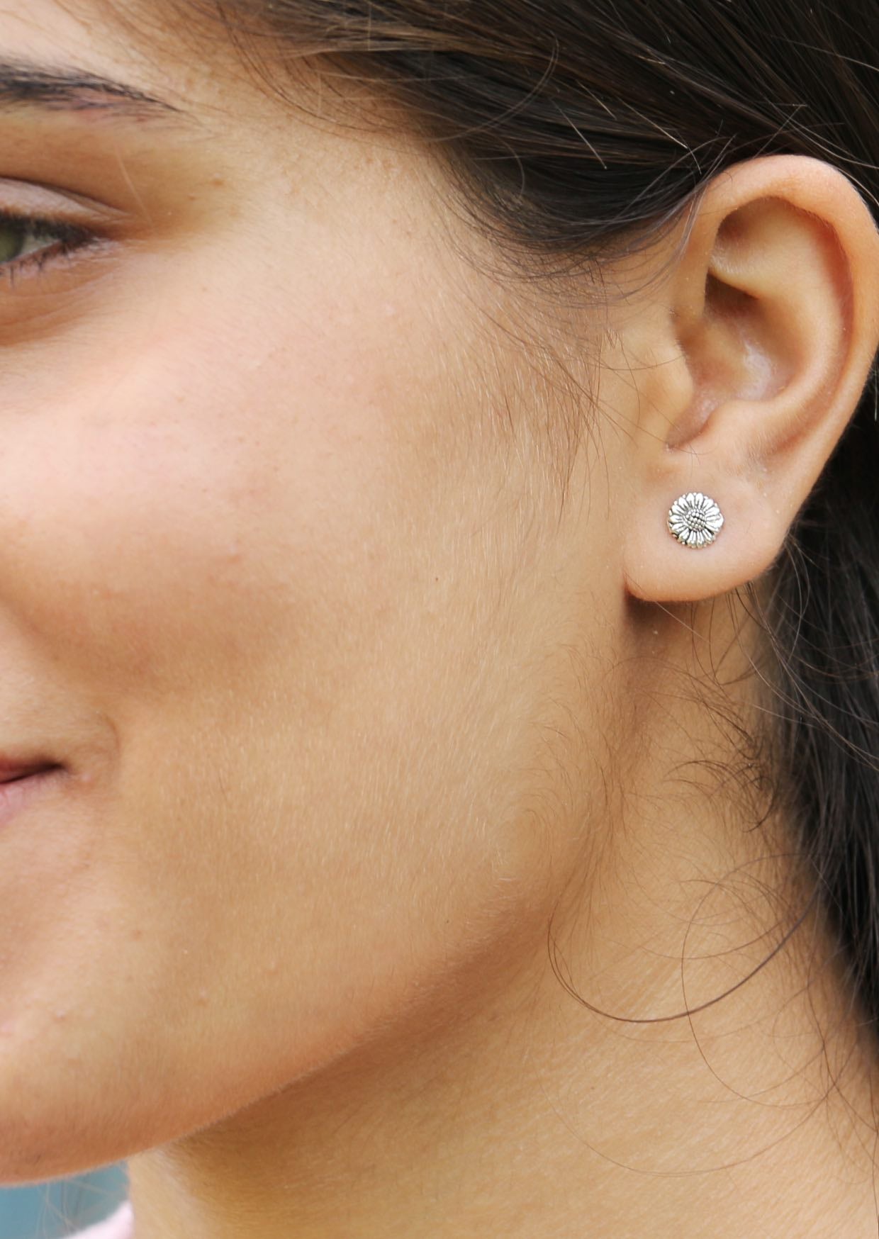 Woman wearing textured sterling silver sunflower studs with detailed petals and centre