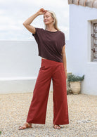 Woman wearing a brown top and burnt henna cotton pants with wide leg fit, pockets and a side zipper