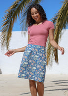 Model wearing knee length dusty blue floral printed reversible skirt with side zipper 