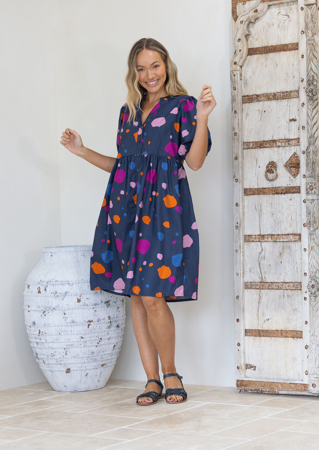 Woman wearing a knee length relaxed fit button through blue dress with elbow length sleeves