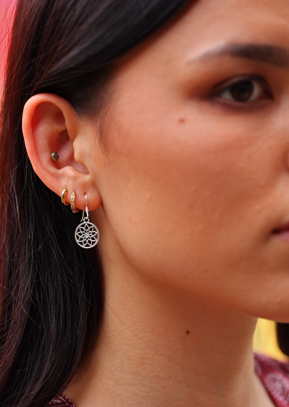 Woman wears sterling silver sacred flower earring with wire hook
