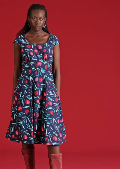 Model wears mid length dress with blue pomegranate print