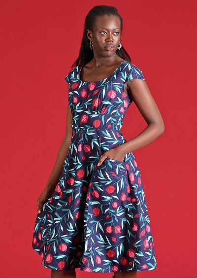 Model wears a 100% cotton mid length dress with a full skirt. This retro inspired dress has a round neck, pockets and cap sleeves