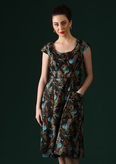 Model wears retro dress with black trim around waistband and pockets