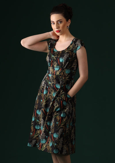 Model wears retro cotton dress with botanical print on black base