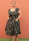 Plus size model wearing retro style cotton dress in black and teal with pockets and full skirt
