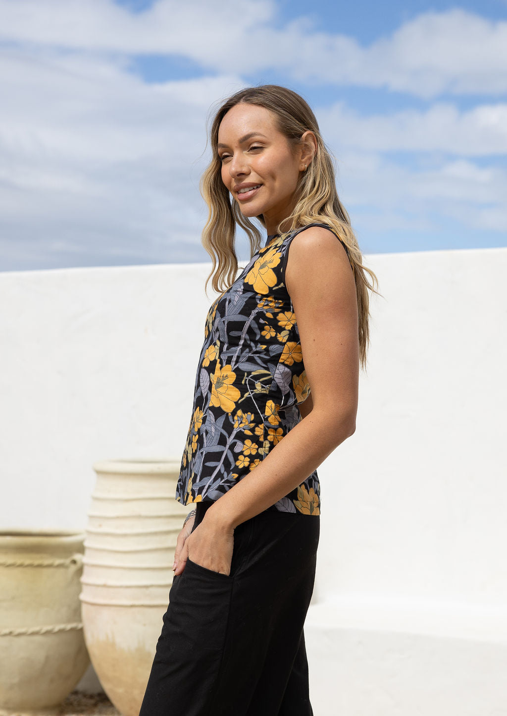 Model poses in a vintage style sleeveless cotton top with plain black trim around the arms and a side zipper 