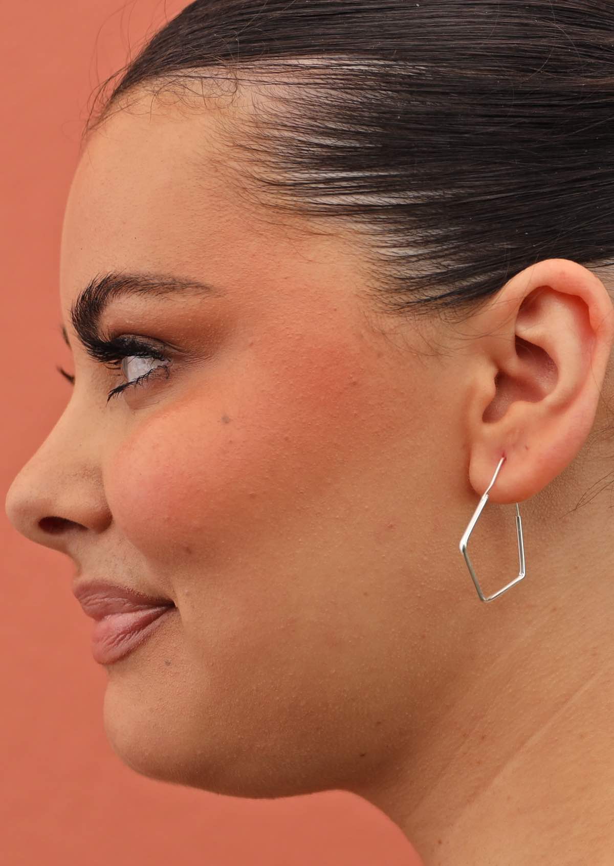 Angular hoop style earring on woman with dark hair