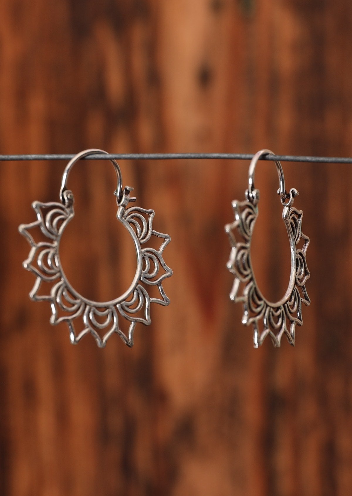 92.5% silver mandala petal earrings hanging on a wire for display. 