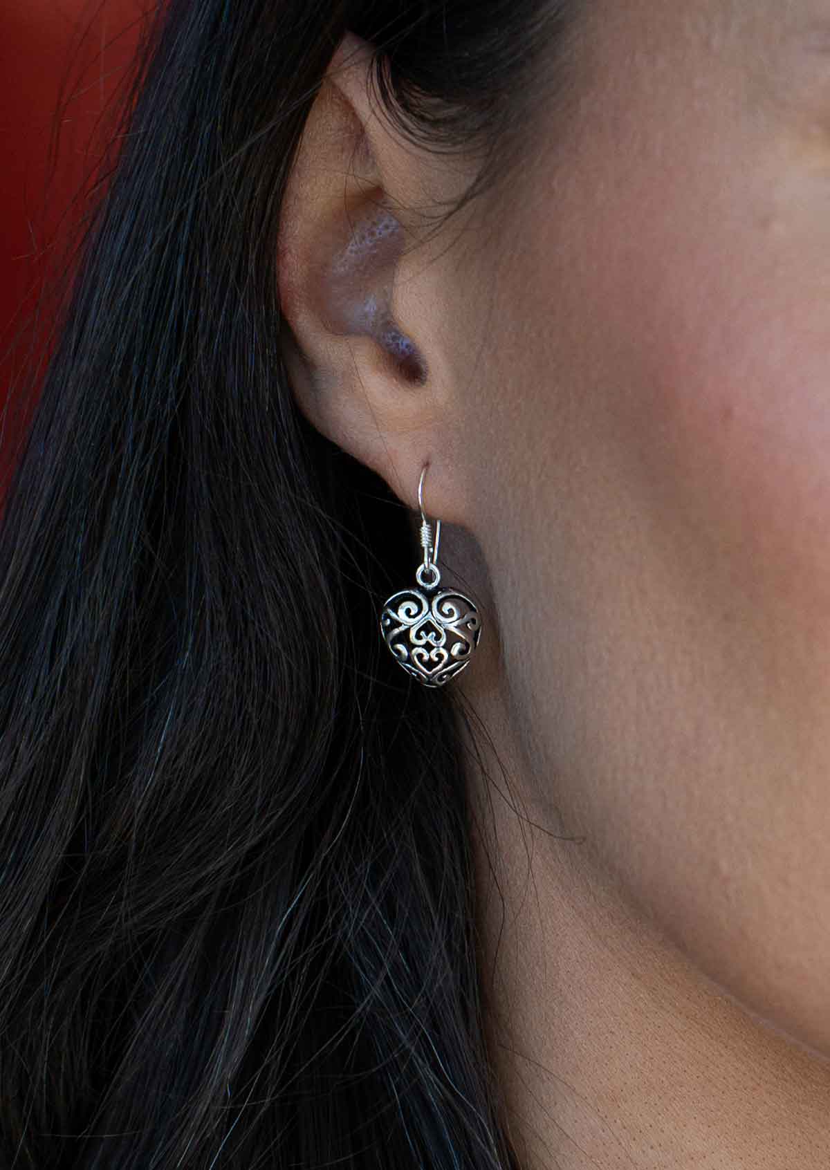  large silver filigree heart earrings on woman's ear
