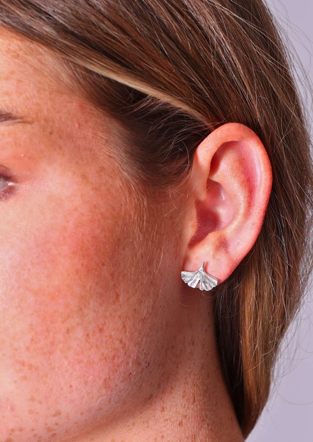 woman wearing sterling silver ginkgo leaf stud earrings 
