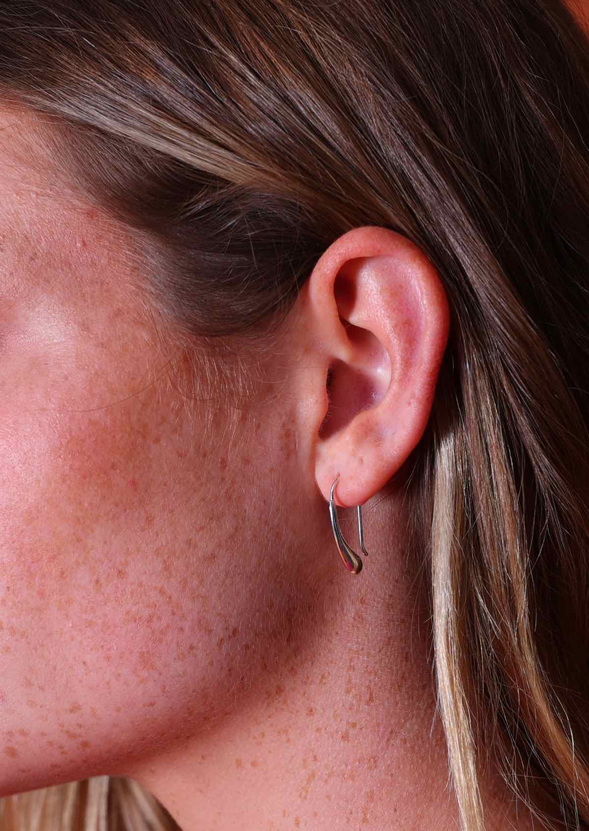 close up of woman wearing silver drop earring 