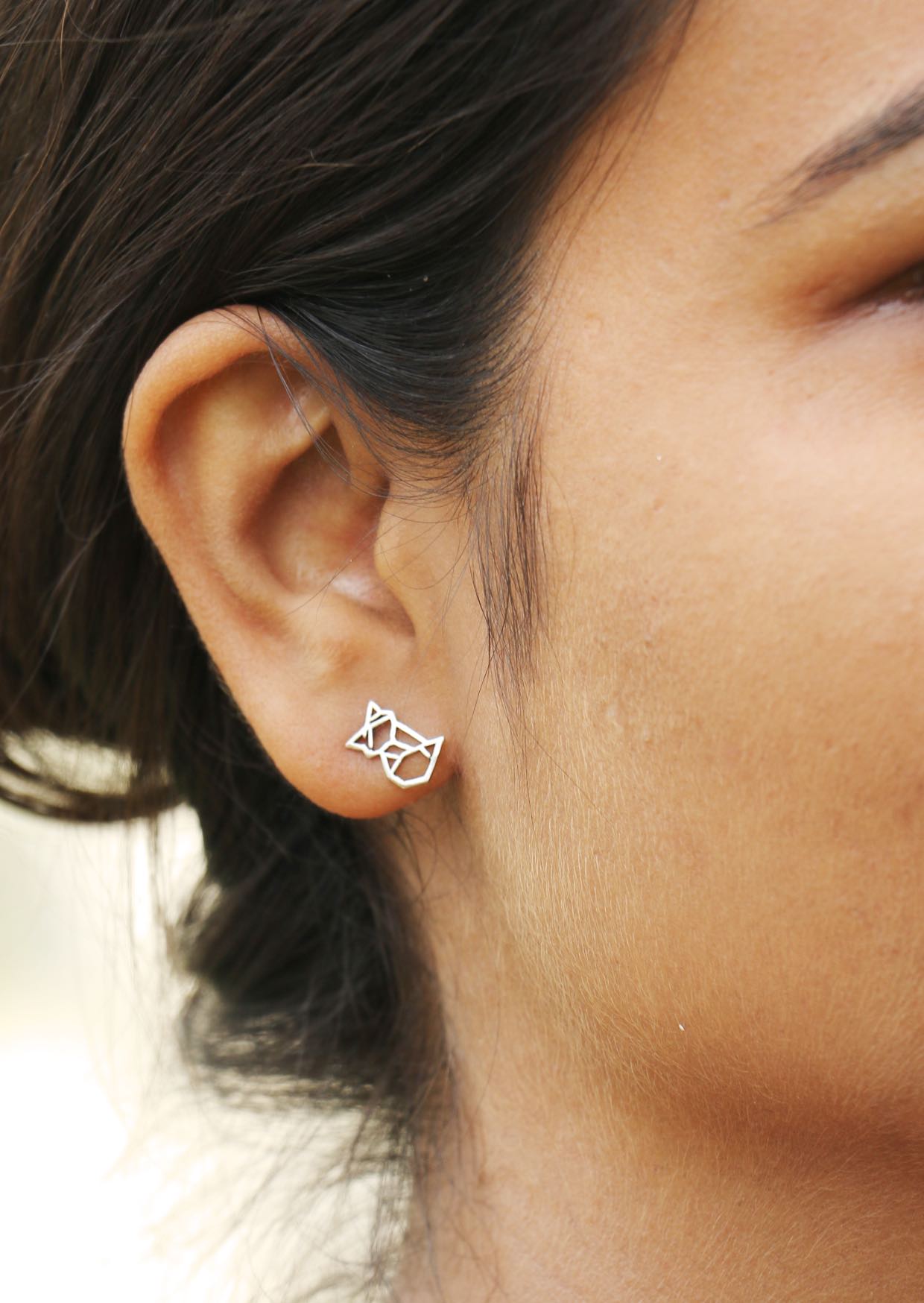 Woman with black hair is wearing sterling silver geometric fox studs with secure butterfly backs