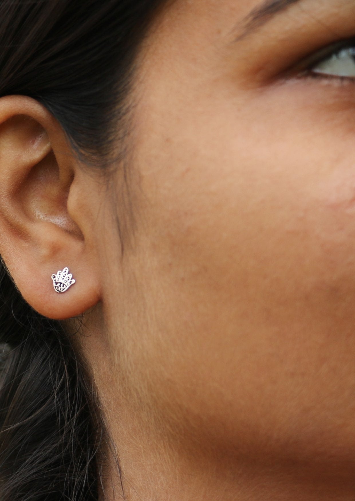 Close up image of woman wearing hand shaped sterling silver studs with delicate lacework details