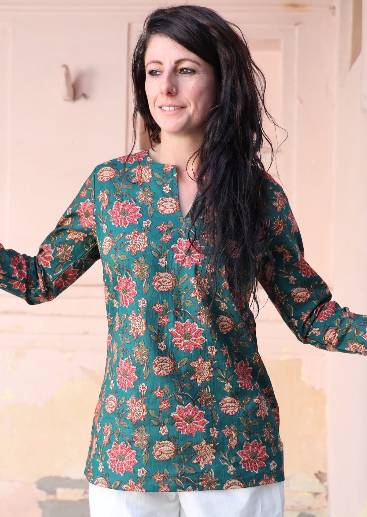 Woman wears a relaxed fit cotton long sleeve top in a green based floral print