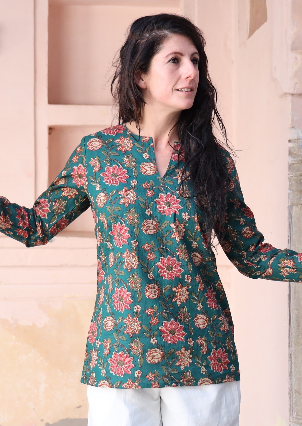Woman wears cotton long sleeve top with keyhole V-cutout, in a green based floral print