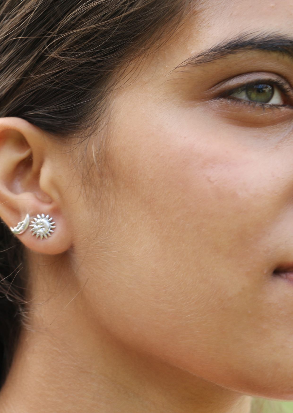 Close up of a woman wearing sun and moon silver studs with delicately imprinted faces