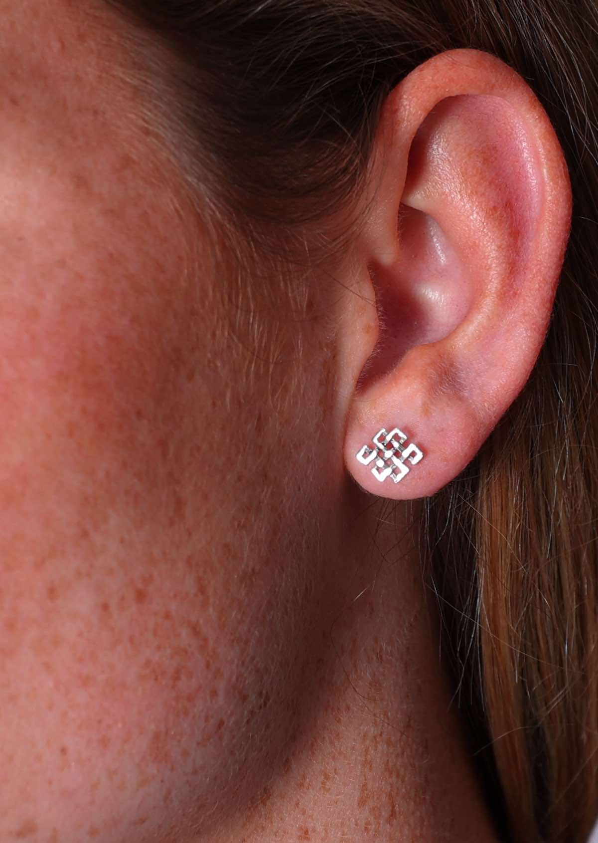 Tibetan Endless Knot sterling silver stud earring in model's ear