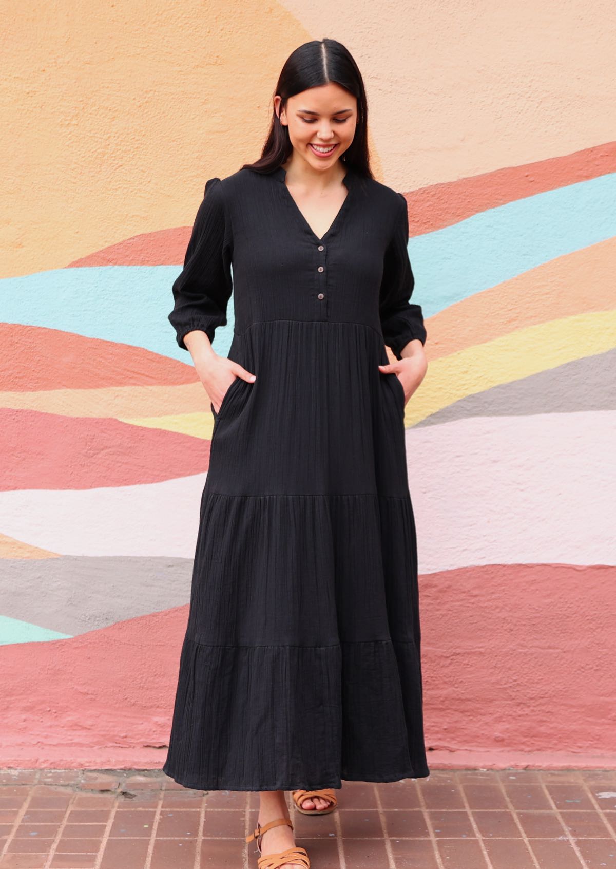 Woman wearing cotton gauze black maxi dress with pockets in front of mural