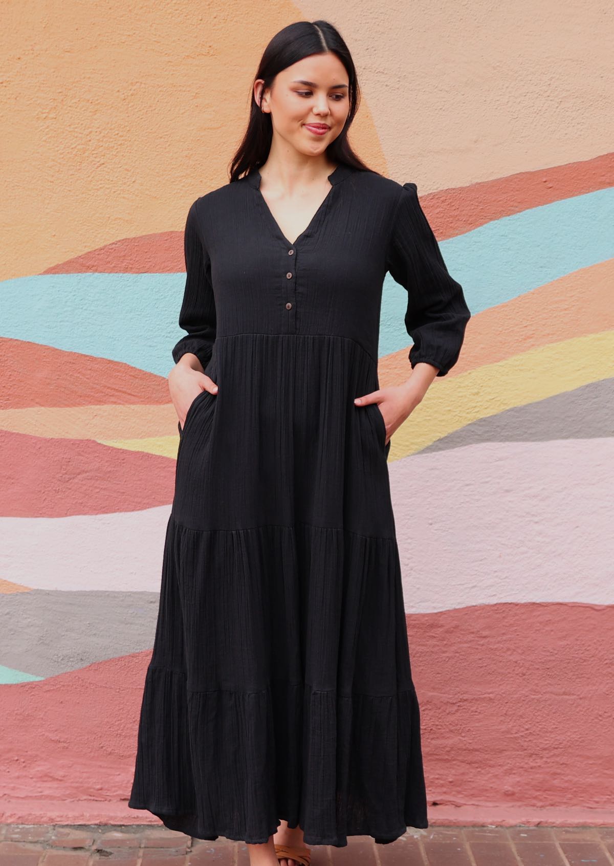 Woman wearing cotton gauze black maxi dress in front of mural

