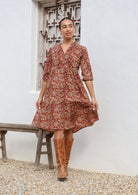 Model walks in cotton tiered over the knee floral print dress, holding the skirt out, paired with tan boots