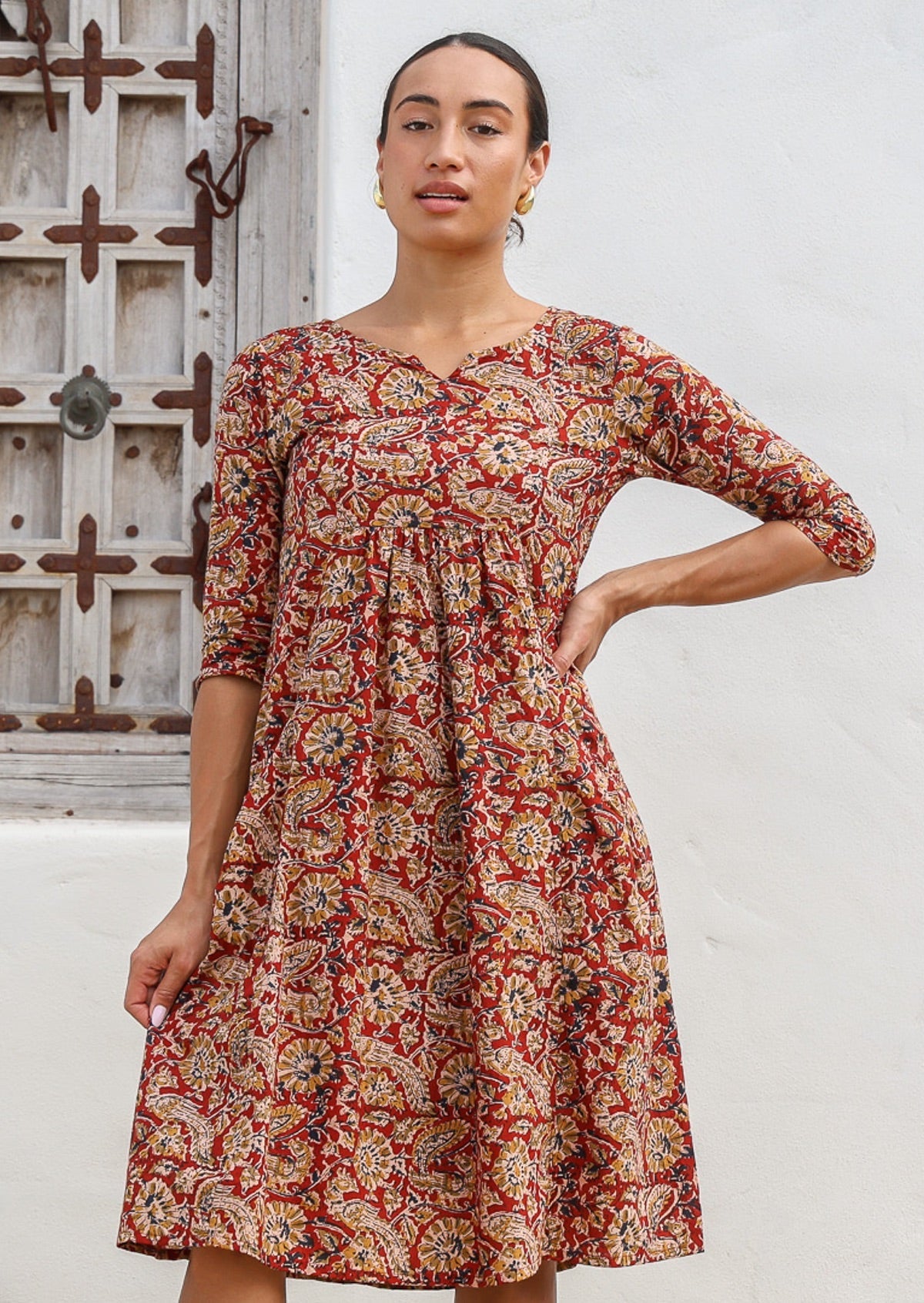 Model wears 100% cotton, midlength dress with earthy floral print, 3/4 sleeves and pockets.