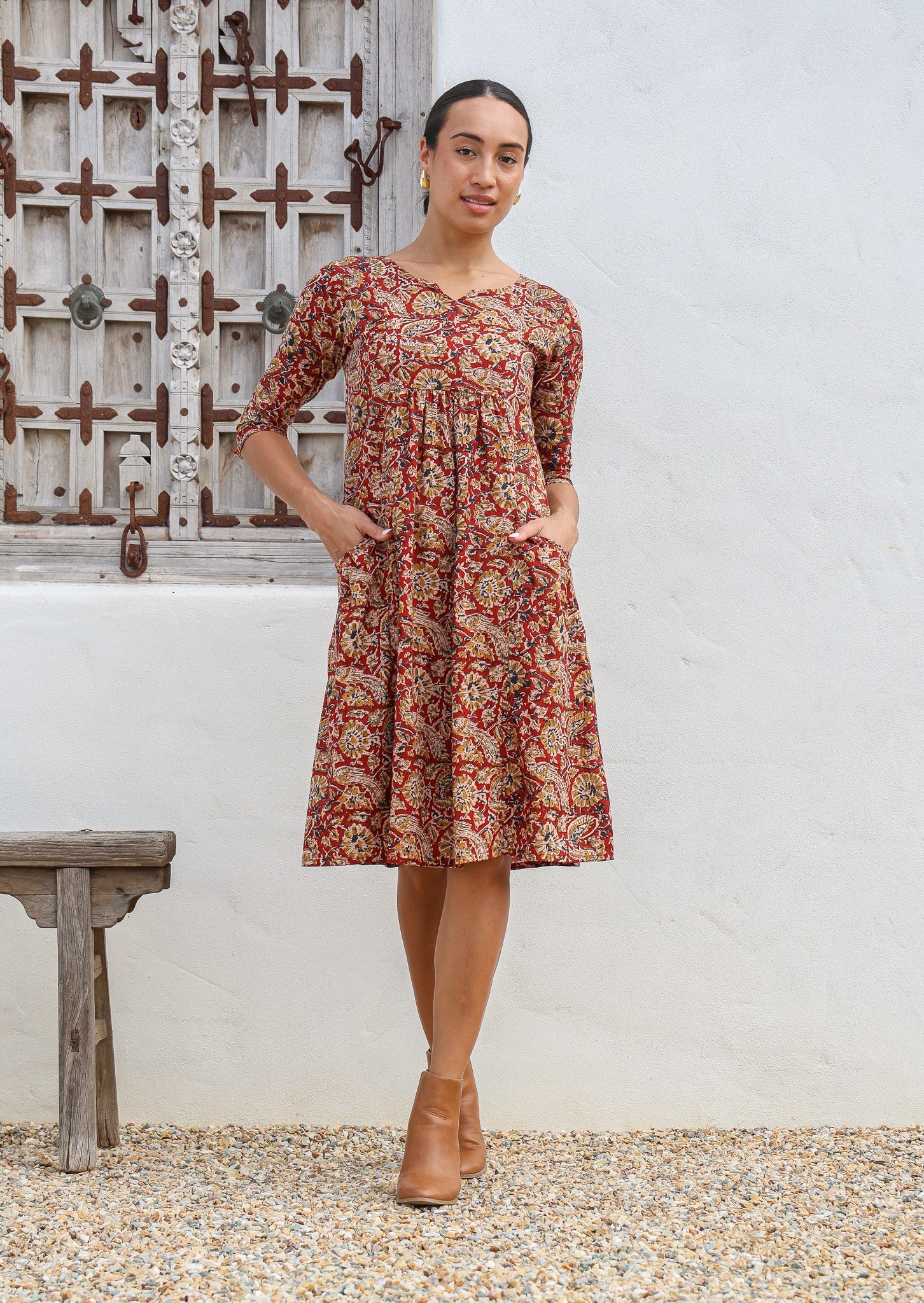 Model wears 100% cotton dress with 3/4 sleeves, round neckline with V cutout and hands in pockets.