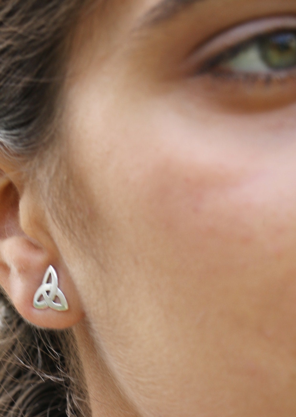 Women wearing a three pointed trinity knot silver studs having the butterfly back