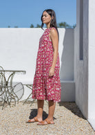 Woman wearing a pink floral cotton midi dress standing outdoors on a sunny day.