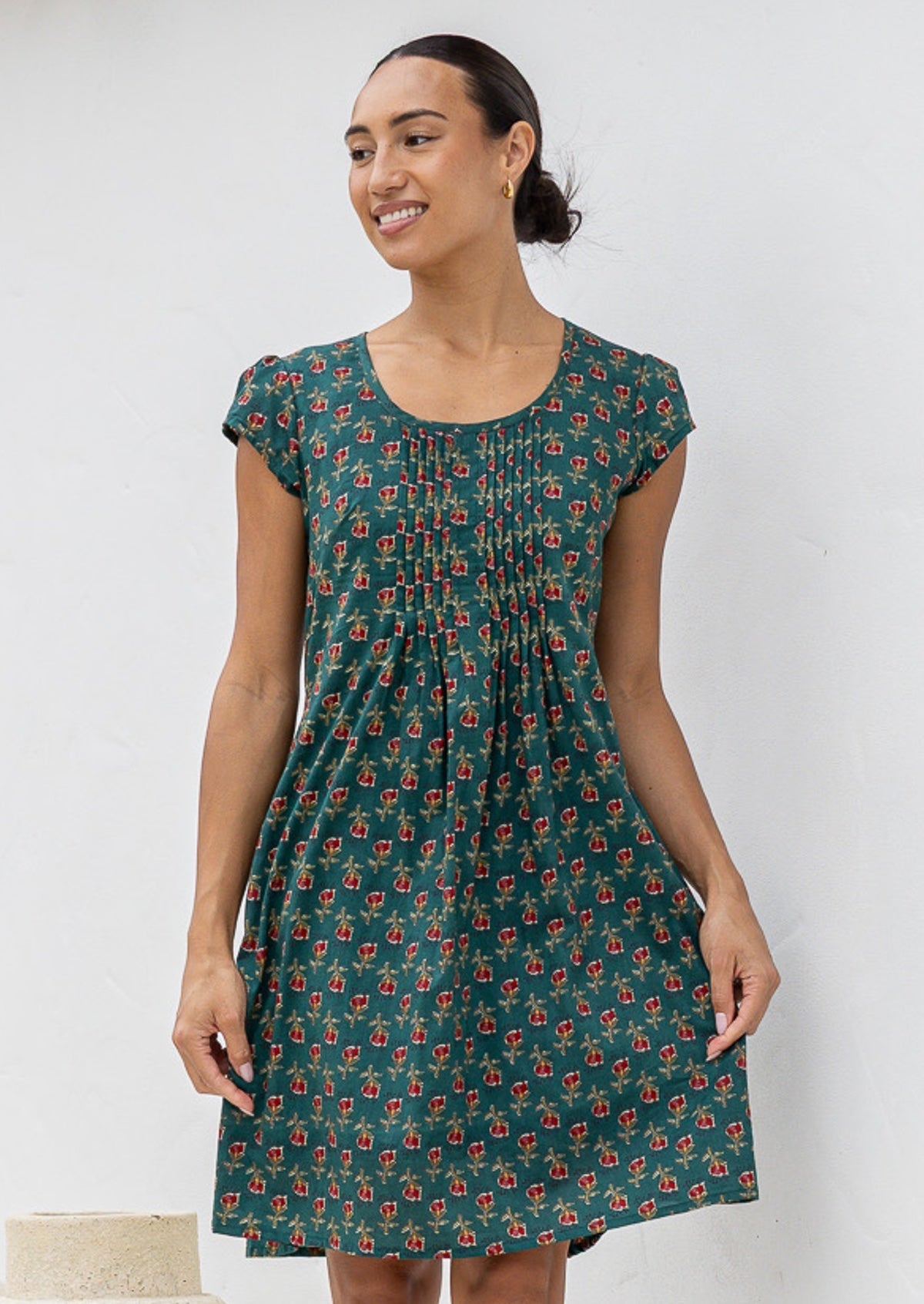 Woman wearing a green floral cotton dress against a white background