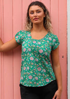Model standing in front of pink door wearing 100 percent cotton short sleeve pleated top 
